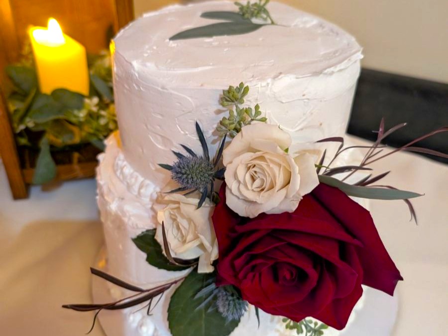 A two-tiered vegan wedding cake with flower decorations.